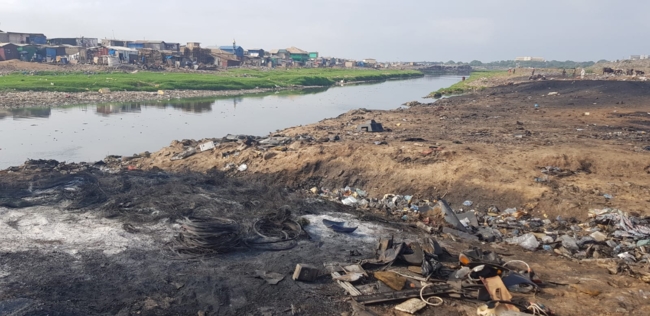 Electronic waste dump in  Agbogbloshie, shacks are seen in the background